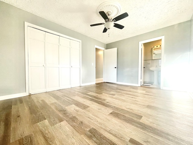 unfurnished bedroom with light hardwood / wood-style floors, a closet, a textured ceiling, and ensuite bathroom