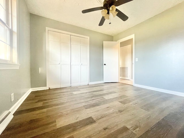 unfurnished bedroom featuring a textured ceiling, light hardwood / wood-style floors, a closet, and ceiling fan