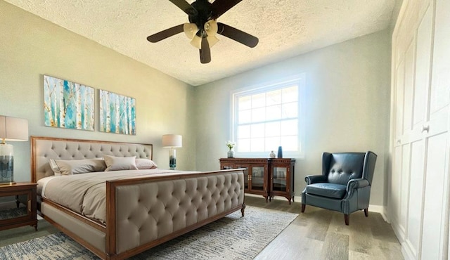 bedroom featuring ceiling fan, wood-type flooring, and a textured ceiling