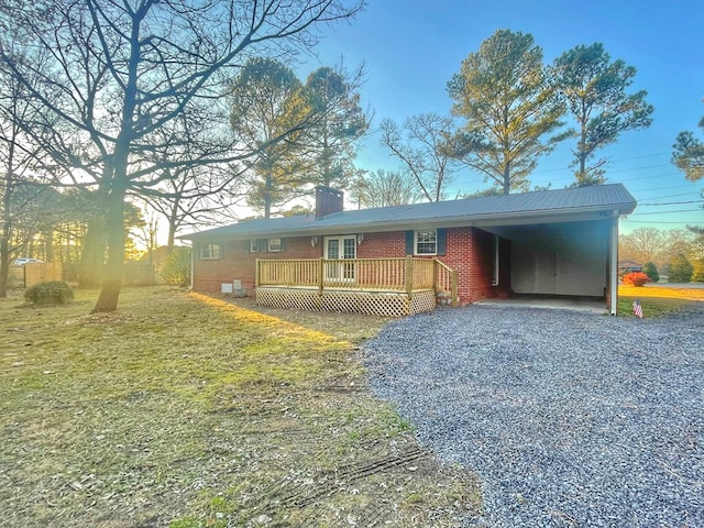 view of front of home with a wooden deck, a carport, and a front yard