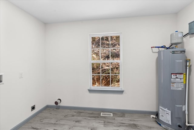 washroom with electric dryer hookup, electric water heater, and light wood-type flooring