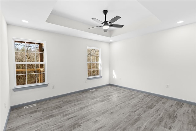 empty room featuring hardwood / wood-style floors, a tray ceiling, and ceiling fan