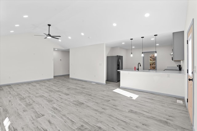 unfurnished living room featuring vaulted ceiling, sink, ceiling fan, and light hardwood / wood-style flooring