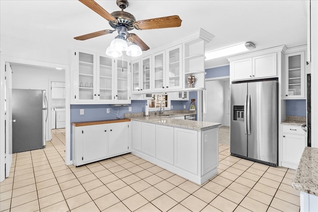 kitchen with white cabinetry, appliances with stainless steel finishes, light tile patterned flooring, and washing machine and dryer