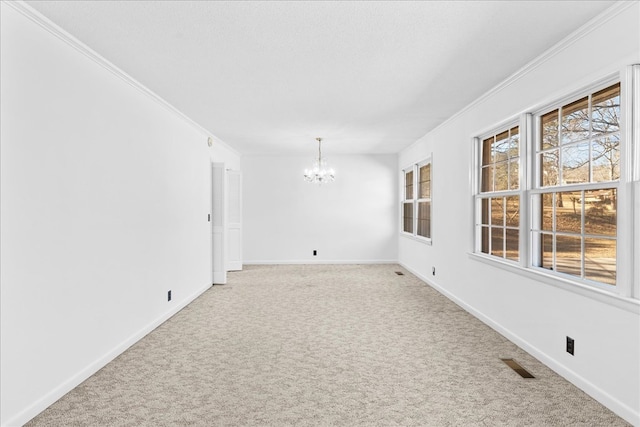 carpeted empty room featuring an inviting chandelier, ornamental molding, and a textured ceiling