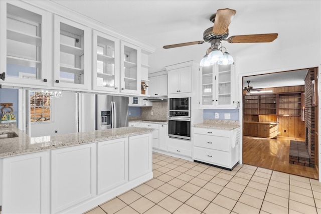 kitchen with light stone counters, ceiling fan, stainless steel appliances, and white cabinets