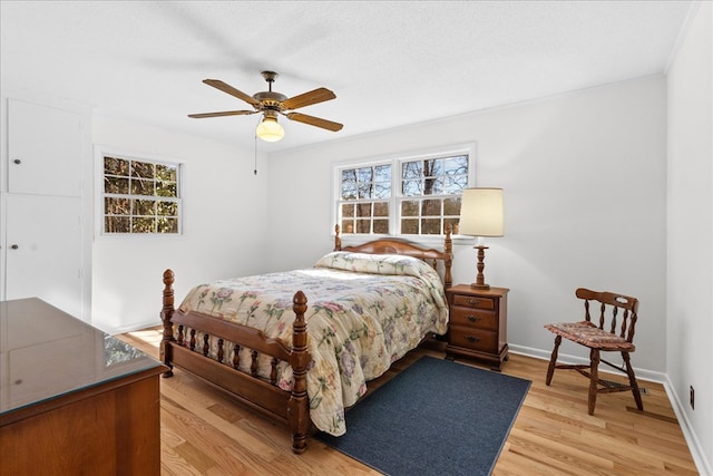 bedroom with ceiling fan, light hardwood / wood-style flooring, ornamental molding, and a textured ceiling