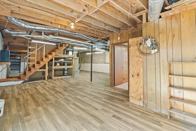 basement featuring washer / dryer, wood-type flooring, and wooden walls