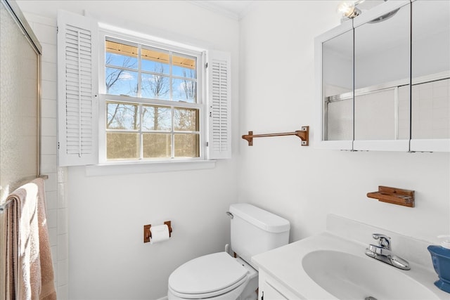 bathroom featuring ornamental molding, vanity, toilet, and a shower with shower door