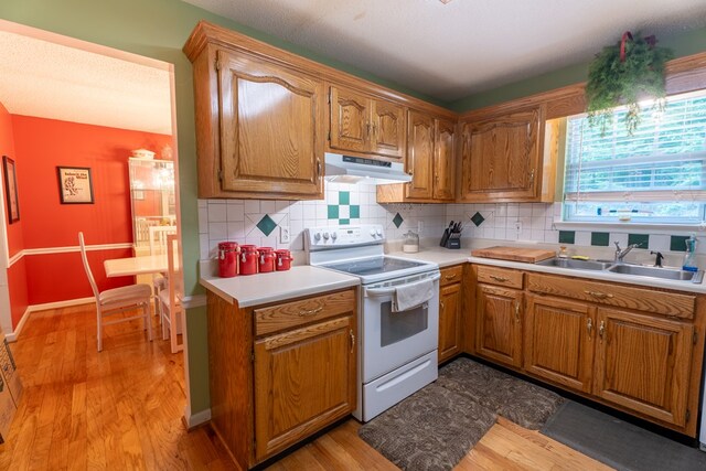 639 Mount View Dr, Tunnel Hill, GA 30755 - kitchen with white electric range oven, under cabinet range hood, a sink, light countertops, and light wood finished floors