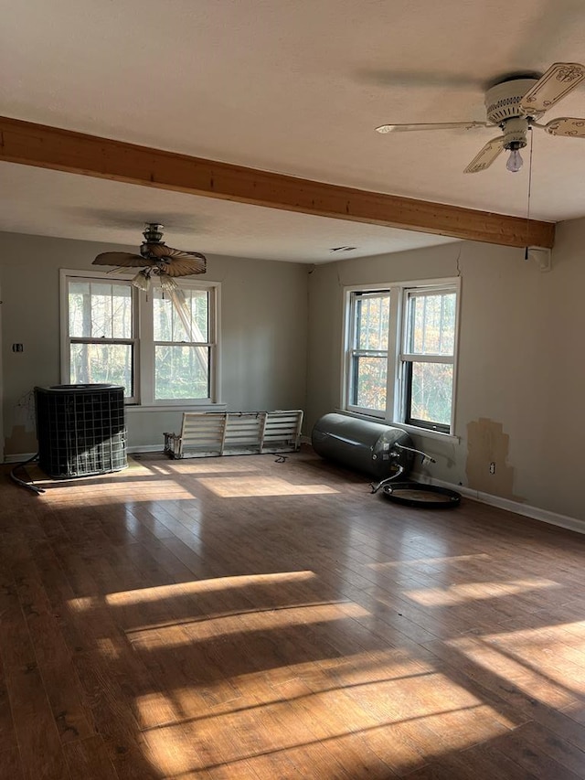 unfurnished room featuring ceiling fan, a healthy amount of sunlight, hardwood / wood-style floors, and beamed ceiling