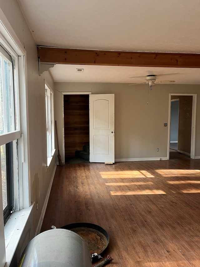 empty room with a ceiling fan, baseboards, beam ceiling, and hardwood / wood-style flooring