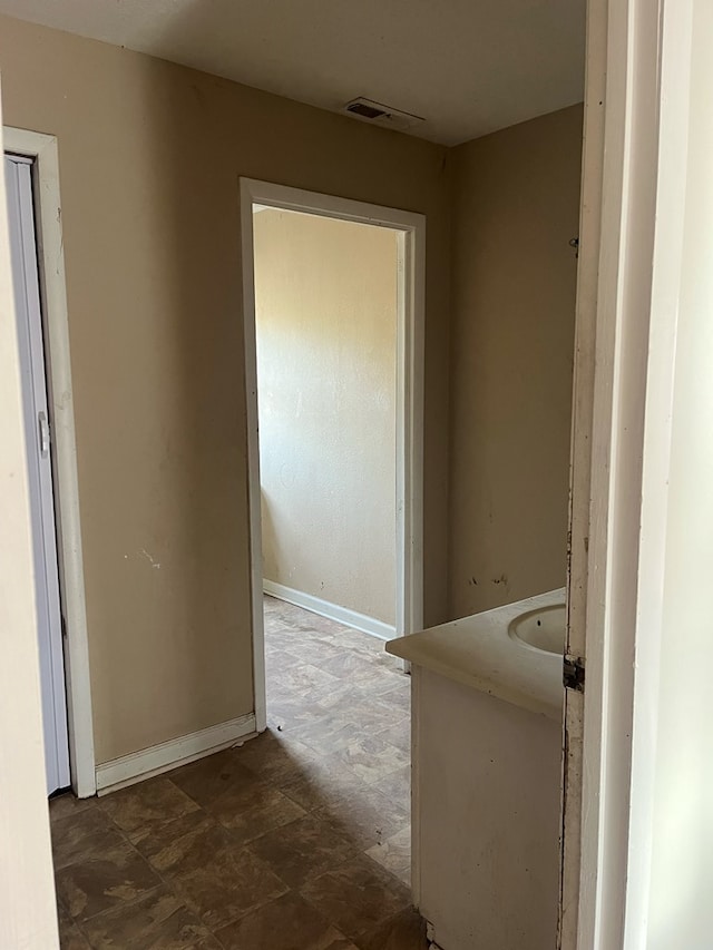 hall featuring baseboards and visible vents