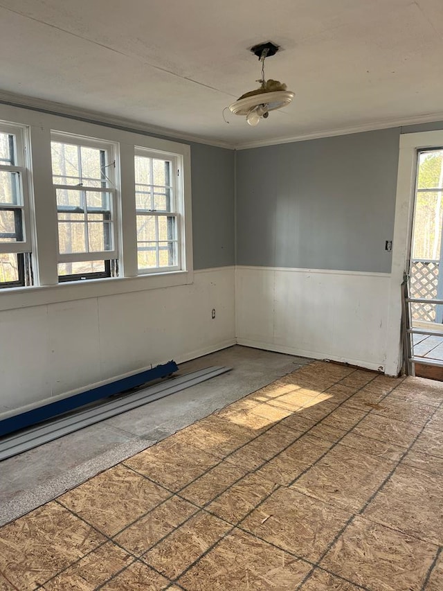 unfurnished room featuring a wainscoted wall and ornamental molding