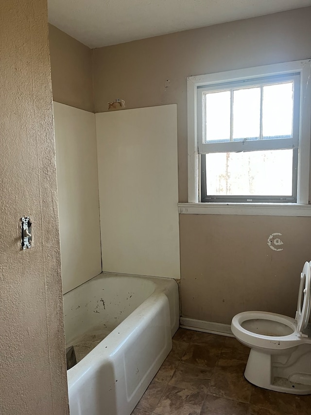 full bath with baseboards, a washtub, and toilet