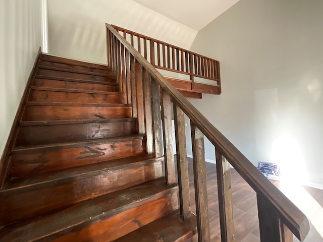 stairs featuring hardwood / wood-style flooring and lofted ceiling