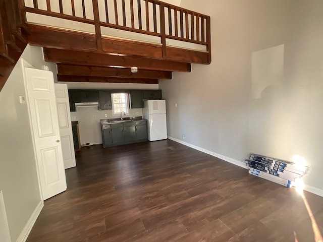 unfurnished living room with beamed ceiling, sink, and dark wood-type flooring