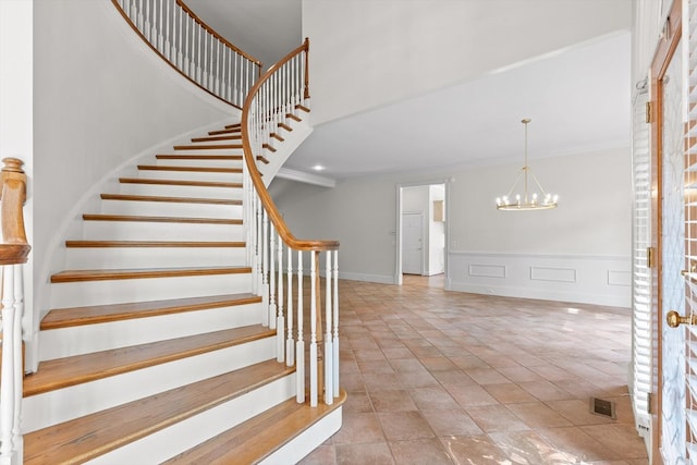 2001 Eagle Point Dr, Dalton, GA 30720 - stairs featuring a chandelier, crown molding, a high ceiling, a decorative wall, and a wainscoted wall