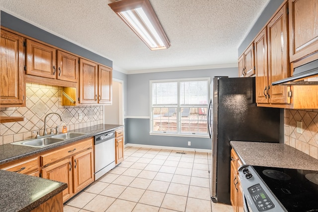 kitchen with dark countertops, crown molding, light tile patterned floors, appliances with stainless steel finishes, and a sink