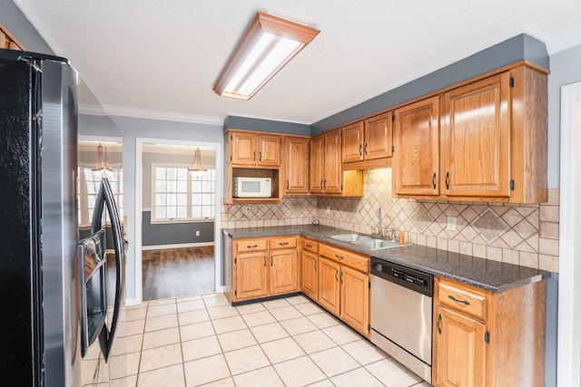 kitchen with dark countertops, light tile patterned floors, decorative backsplash, appliances with stainless steel finishes, and a sink