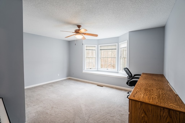 unfurnished office featuring carpet, baseboards, visible vents, ceiling fan, and a textured ceiling