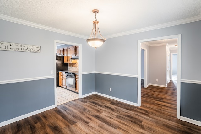 spare room featuring crown molding, wood finished floors, and baseboards