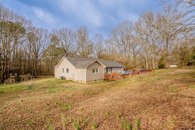 view of side of property featuring a shingled roof, central AC, a yard, a deck, and crawl space