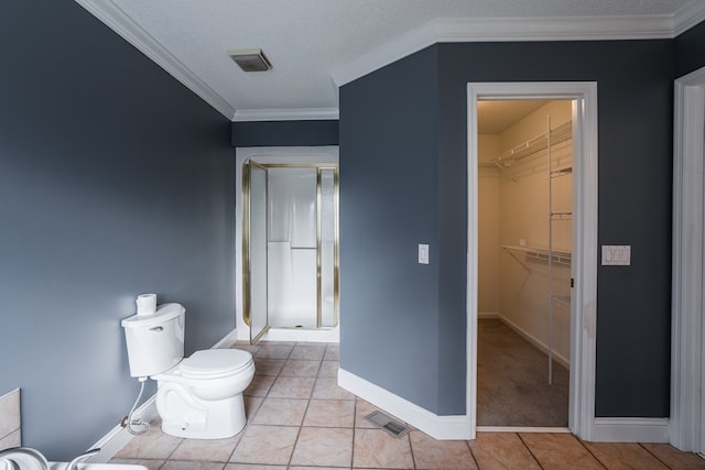 full bathroom featuring tile patterned flooring, crown molding, toilet, and a stall shower