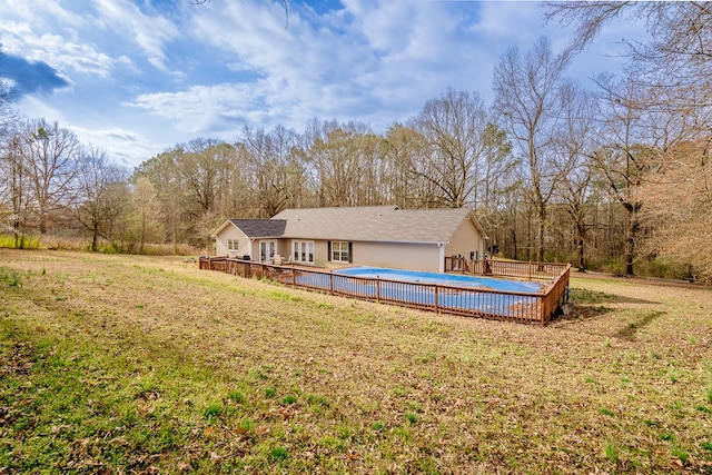 exterior space featuring a wooden deck, a yard, and a fenced in pool