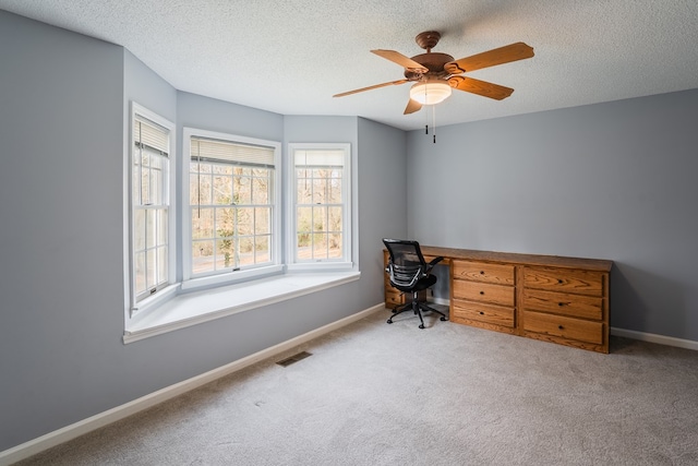 home office with visible vents, a textured ceiling, carpet floors, baseboards, and ceiling fan