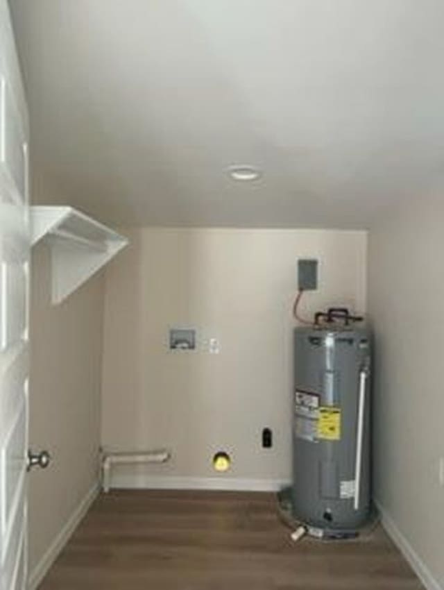 clothes washing area with dark hardwood / wood-style floors and electric water heater