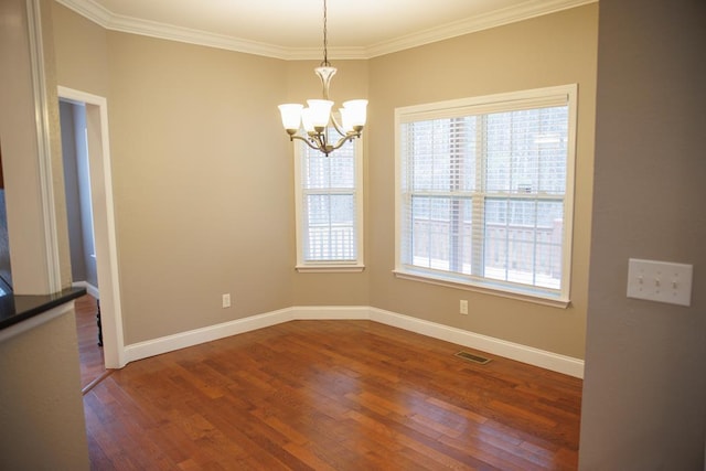 unfurnished dining area with crown molding, hardwood / wood-style floors, and a notable chandelier