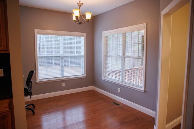 unfurnished office featuring hardwood / wood-style floors and an inviting chandelier