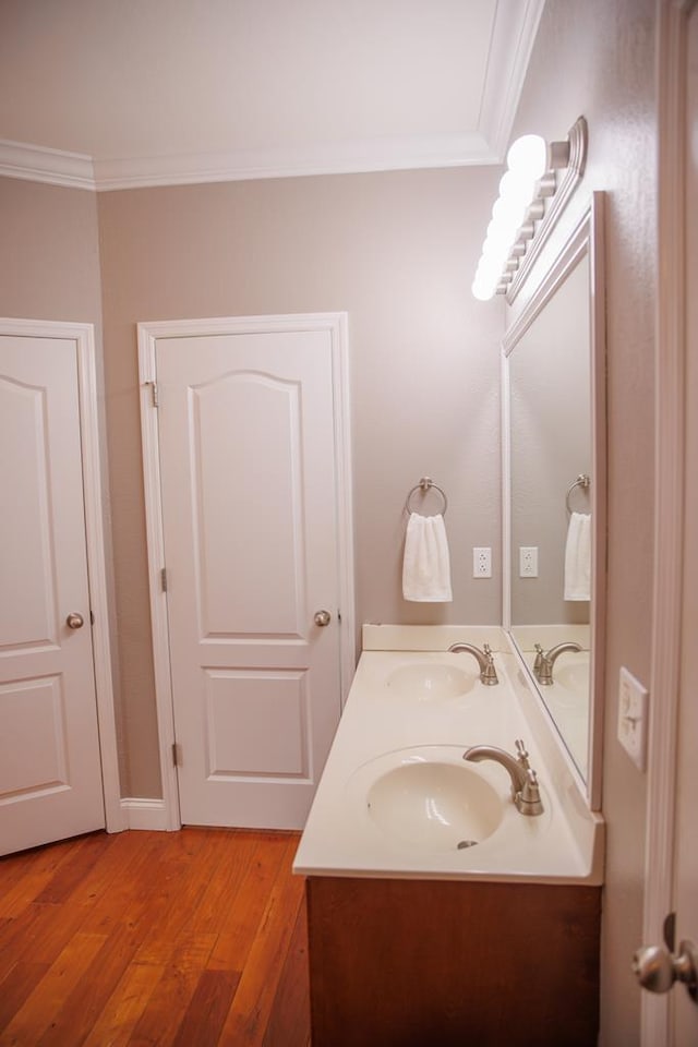 bathroom featuring crown molding, wood-type flooring, and vanity