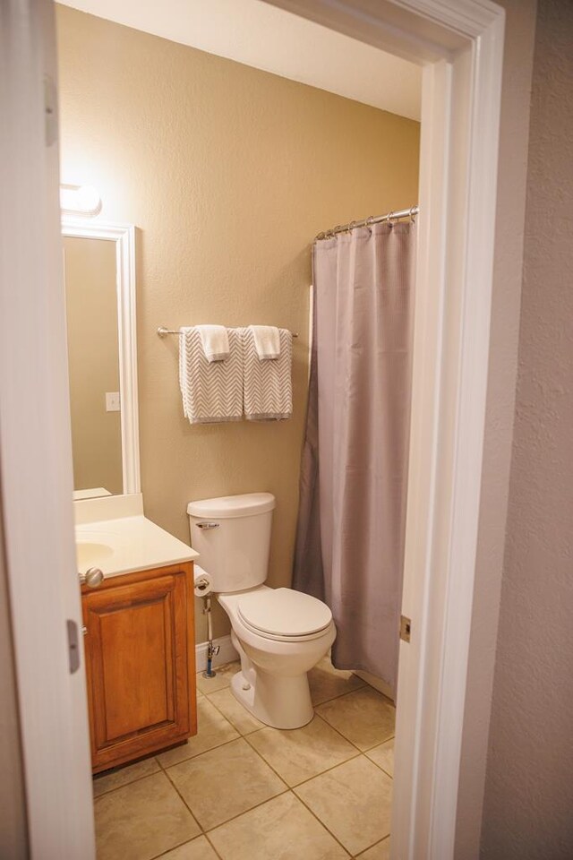 bathroom featuring tile patterned flooring, vanity, toilet, and a shower with shower curtain