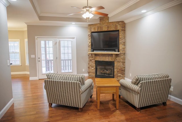 living room with a fireplace, crown molding, wood-type flooring, and ceiling fan