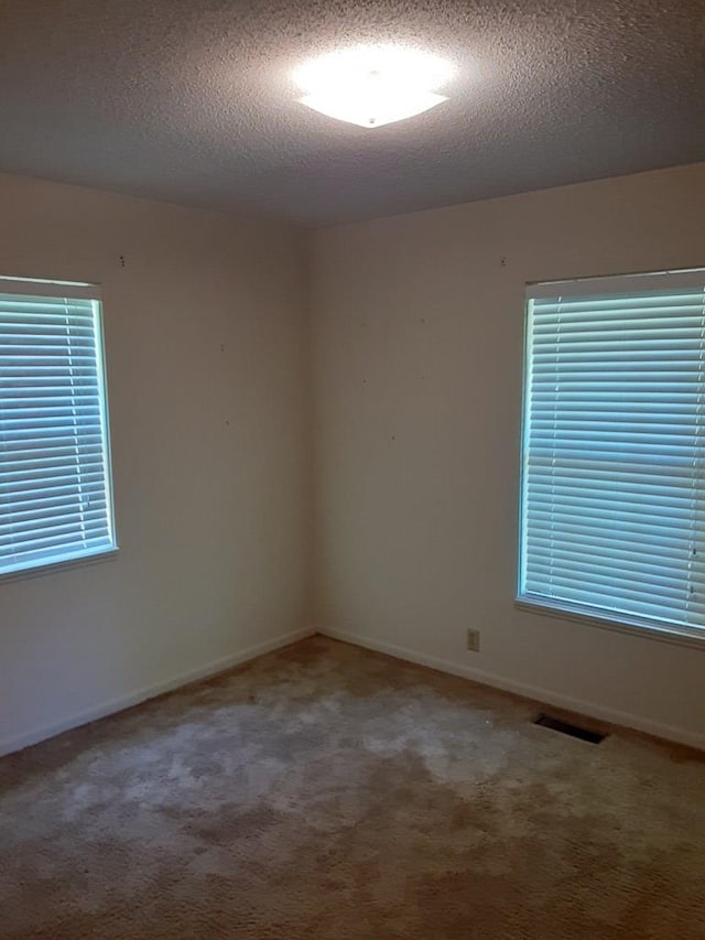 carpeted empty room with a textured ceiling