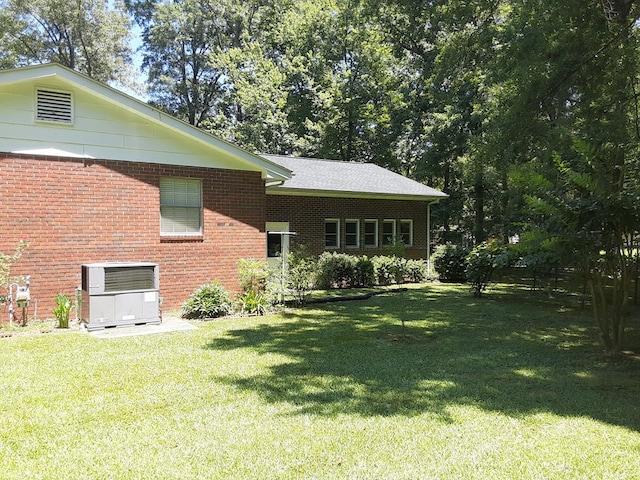 rear view of house featuring central AC and a lawn