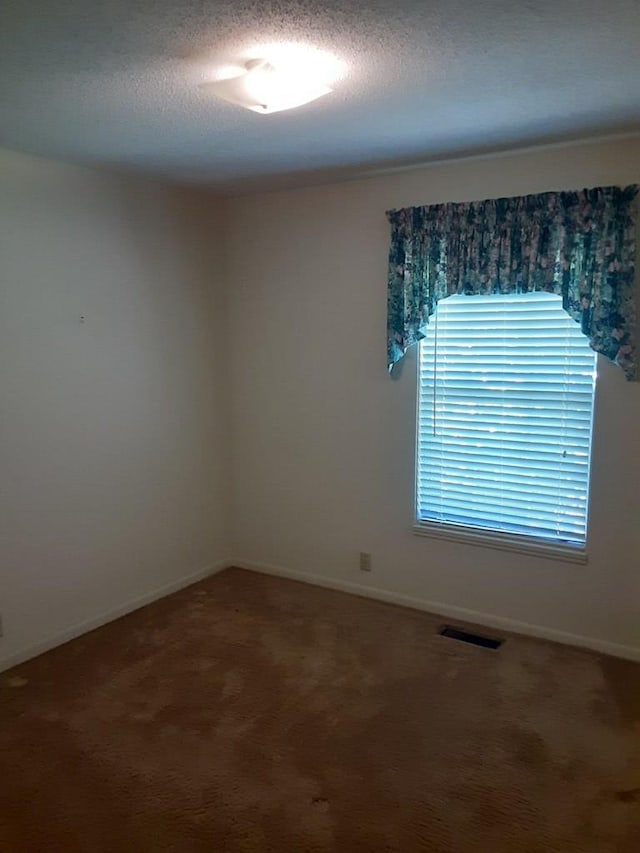 carpeted spare room with a textured ceiling