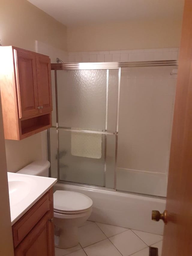 full bathroom with tile patterned flooring, bath / shower combo with glass door, vanity, and toilet