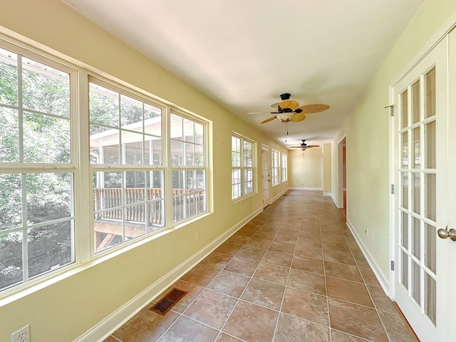 unfurnished sunroom with ceiling fan