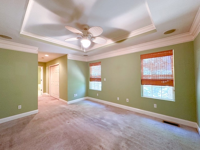 carpeted empty room featuring crown molding, ceiling fan, and a tray ceiling