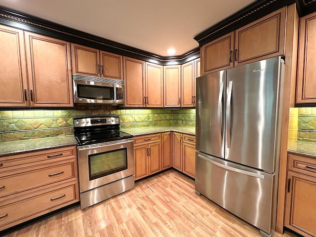 kitchen with tasteful backsplash, appliances with stainless steel finishes, light hardwood / wood-style flooring, and stone counters