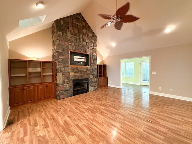 living room featuring ceiling fan, a stone fireplace, high vaulted ceiling, and light hardwood / wood-style flooring