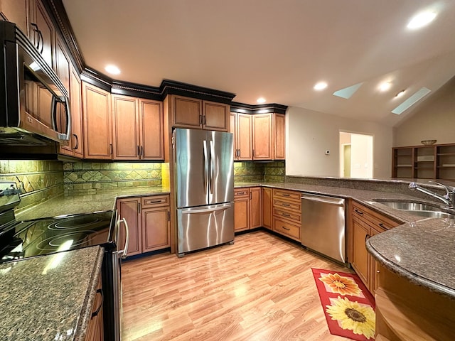 kitchen featuring sink, vaulted ceiling, light wood-type flooring, kitchen peninsula, and stainless steel appliances