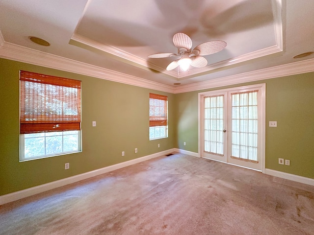 carpeted spare room featuring crown molding, a tray ceiling, french doors, and ceiling fan