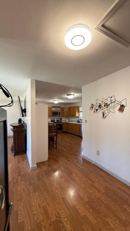 hallway featuring visible vents, baseboards, and dark wood-style flooring