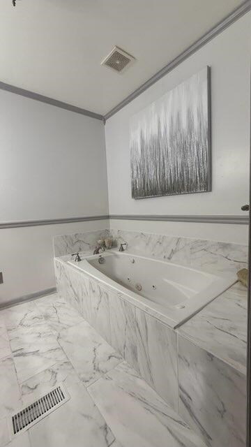 full bathroom with visible vents, marble finish floor, a whirlpool tub, and ornamental molding