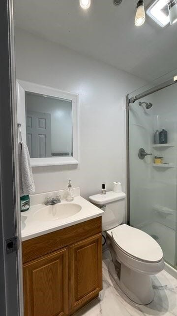 full bath with vanity, toilet, a stall shower, and marble finish floor