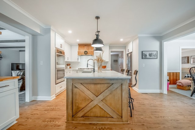 kitchen featuring a breakfast bar, pendant lighting, double oven, white cabinets, and light hardwood / wood-style floors